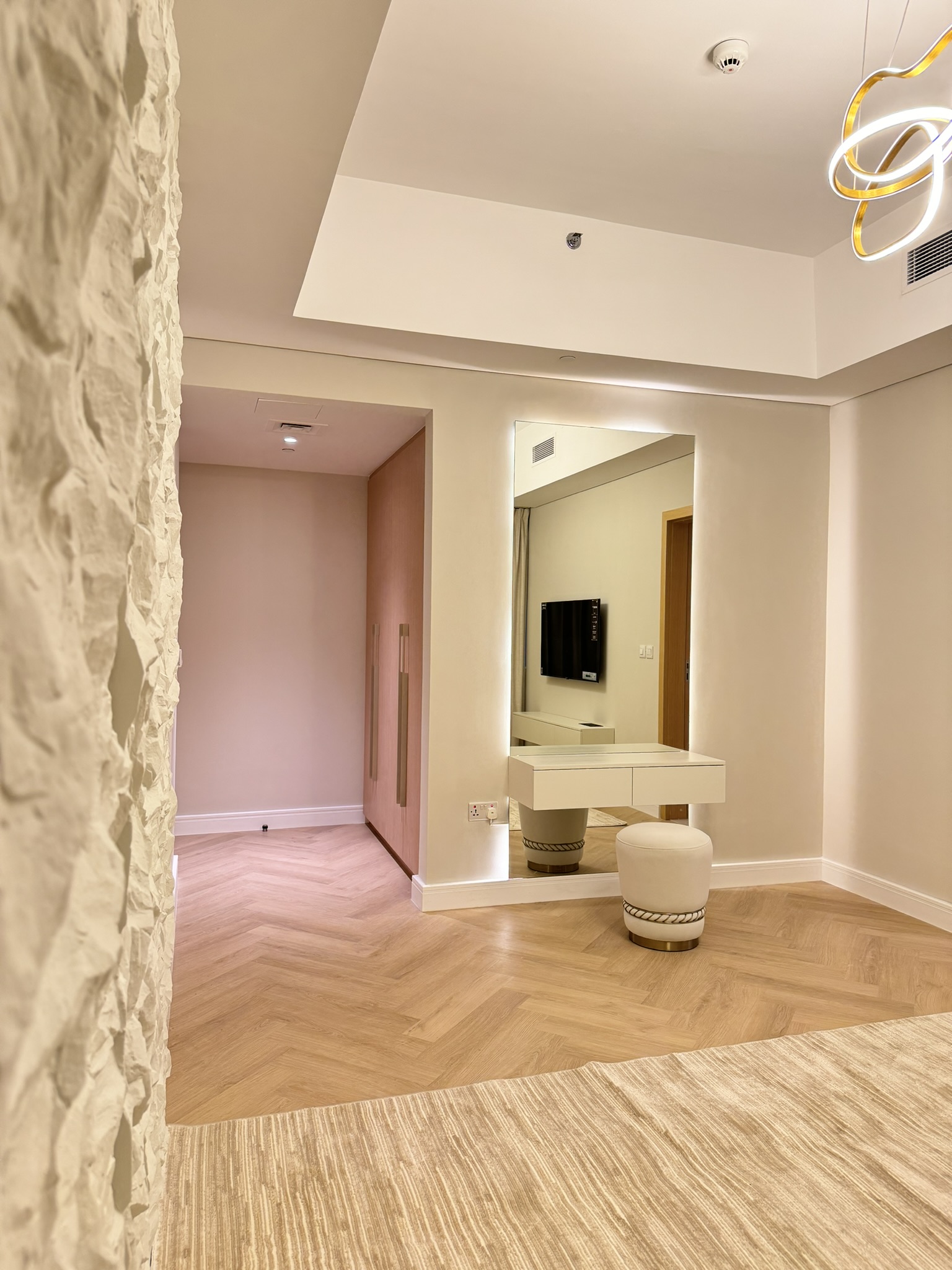 View past a textured wall toward the illuminated dressing mirror at Lisa Villa