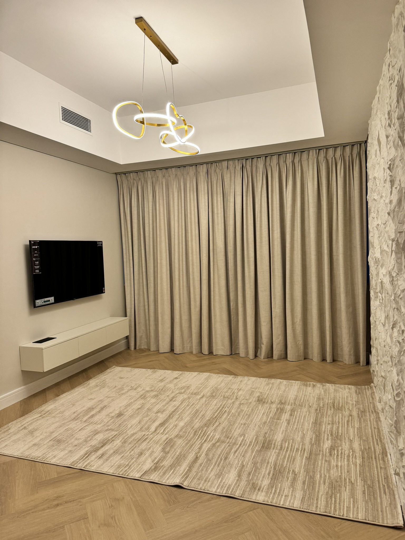 Lisa Villa living room with full-height curtains, a television and sculptural pendant light