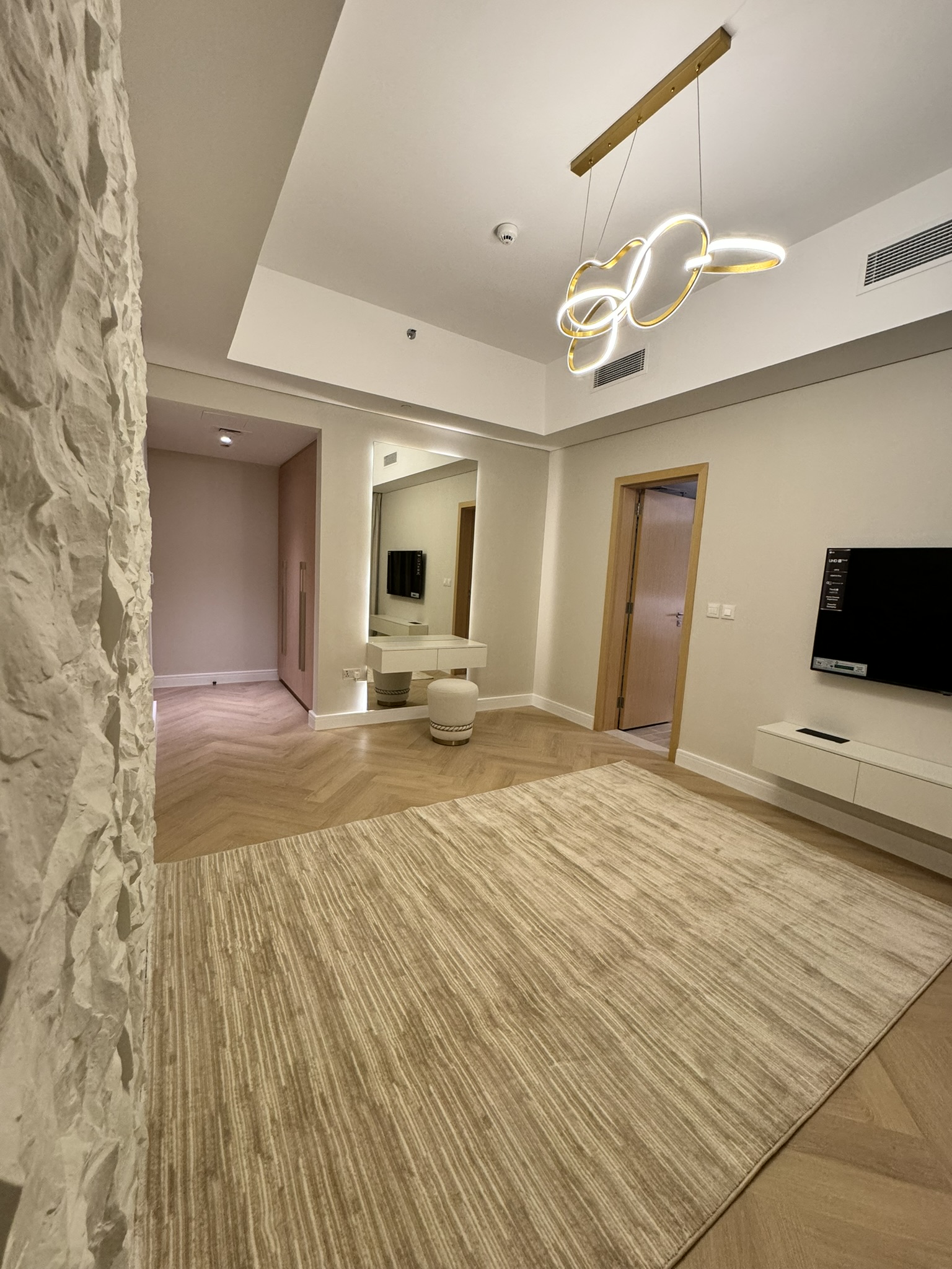 Lisa Villa room showing a textured feature wall, television console and dressing area